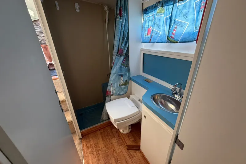 Slide: The Image of 1973 Chris-Craft 31 Sedan Cruiser bathroom with sink, toilet, and nautical-themed curtains. - 51
