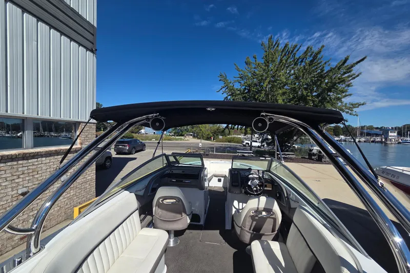 Slide: The Image of 2005 Cobalt 272 boat interior with seating, steering wheel, and canopy under clear blue sky. - 22