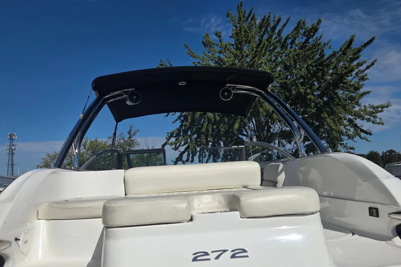 Slide: The Image of 2005 Cobalt 272 boat with white seating and black canopy under clear blue sky. - 14