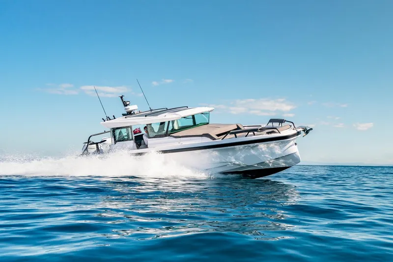 The Image of 2027 Axopar 38 XC Cross Cabin cruising on open water under clear blue skies. - 0