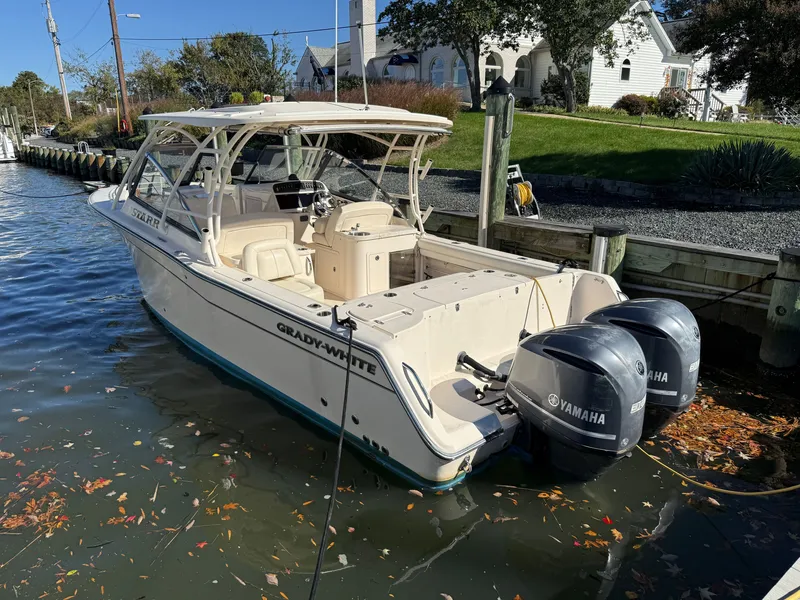 Slide: The Image of 2015 Grady-White Freedom 307 with twin Yamaha engines, docked along a calm waterway. - 2