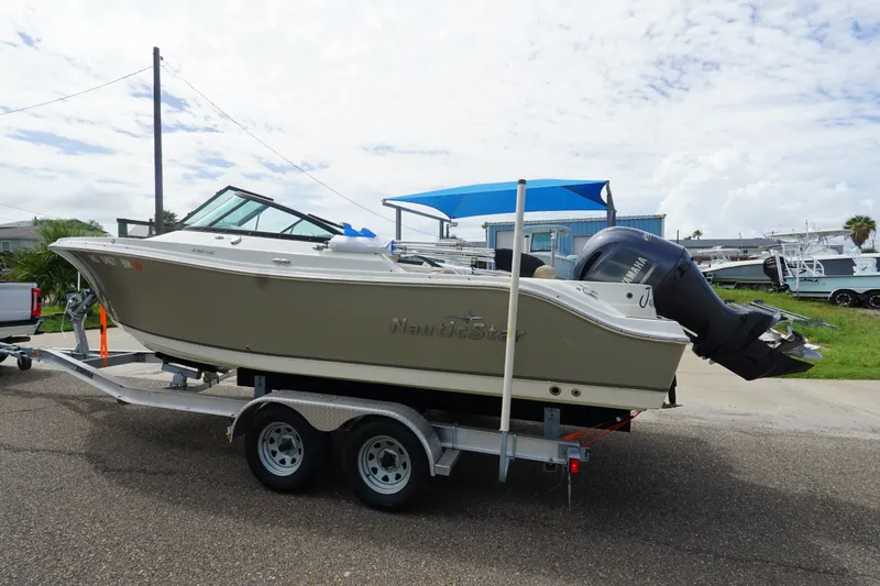 Slide: The Image of 2020 NauticStar 2302 Legacy Dual Console boat on trailer, parked outdoors. - 3