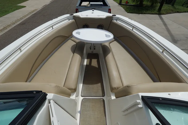 Slide: The Image of 2020 NauticStar 2302 Legacy Dual Console boat interior with beige seating and round table. - 12
