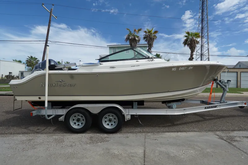 Slide: The Image of 2020 NauticStar 2302 Legacy Dual Console boat on trailer, parked outdoors. - 4