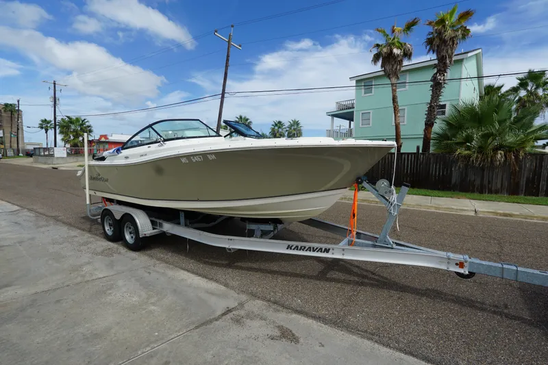 Slide: The Image of 2020 NauticStar 2302 Legacy Dual Console boat on trailer, parked on street with palm trees. - 5