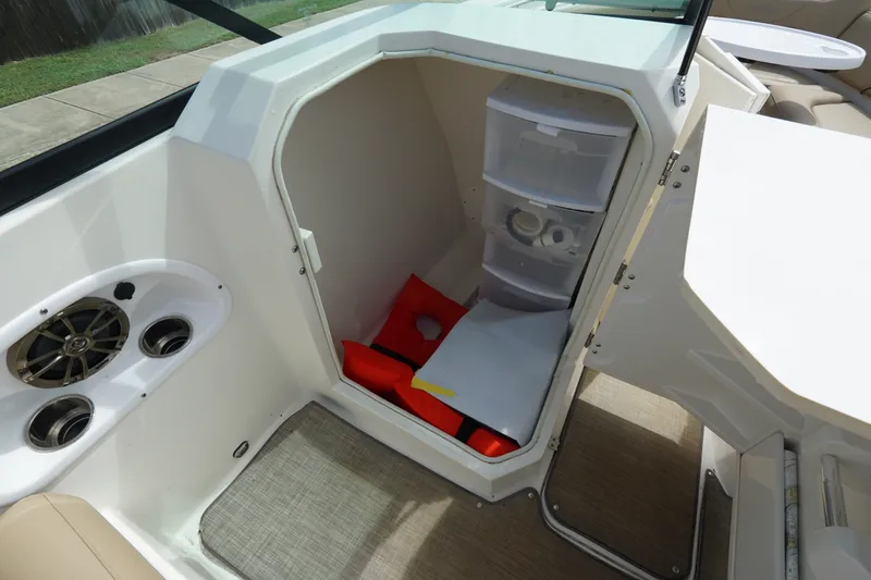 Slide: The Image of 2020 NauticStar 2302 Legacy Dual Console storage area with life jackets and supplies. - 18
