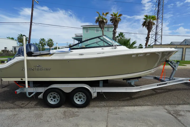 The Image of 2020 NauticStar 2302 Legacy Dual Console boat on trailer, parked outdoors. - 0