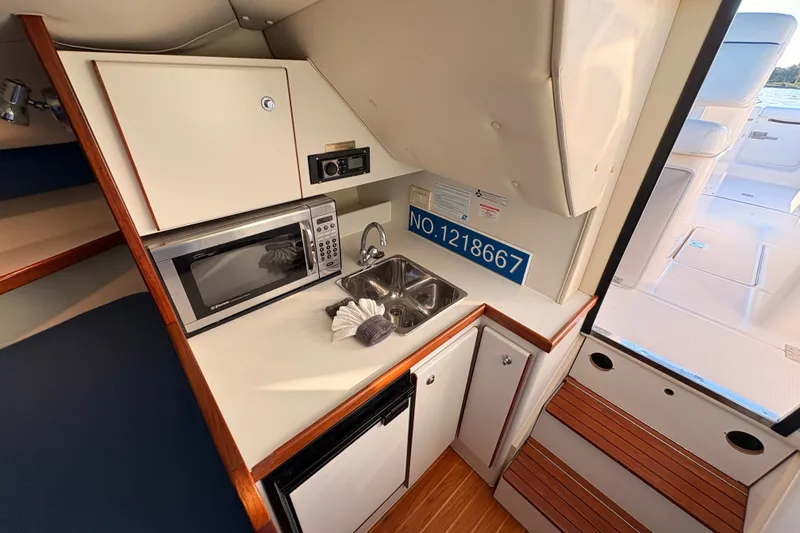 Slide: The Image of 2003 Tiara Yachts 2900 Coronet interior with kitchenette, microwave, sink, and wooden accents. - 49