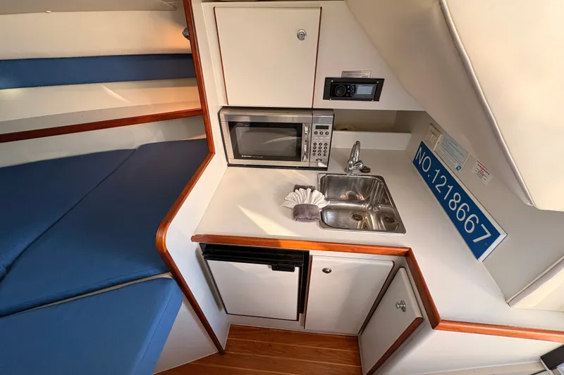 Slide: The Image of 2003 Tiara Yachts 2900 Coronet interior with kitchenette, sink, and blue seating. - 54