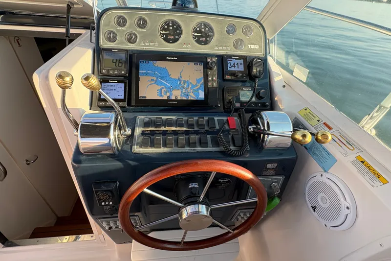 Slide: The Image of Helm of 2003 Tiara Yachts 2900 Coronet with navigation controls and wooden steering wheel. - 50