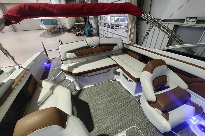 Slide: The Image of 2020 Four Winns HD220 boat interior with white and brown seating, under red canopy. - 19