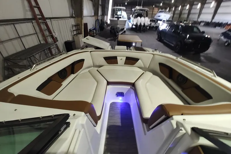 Slide: The Image of 2020 Four Winns HD220 boat interior with cushioned seating and ambient lighting in a storage facility. - 13