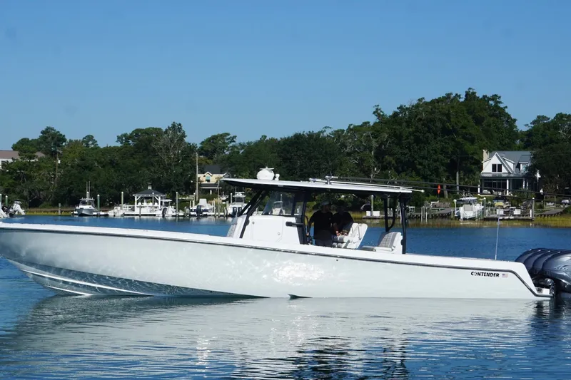 Slide: The Image of 2023 Contender 44 ST boat on calm water, surrounded by lush greenery and waterfront homes. - 5
