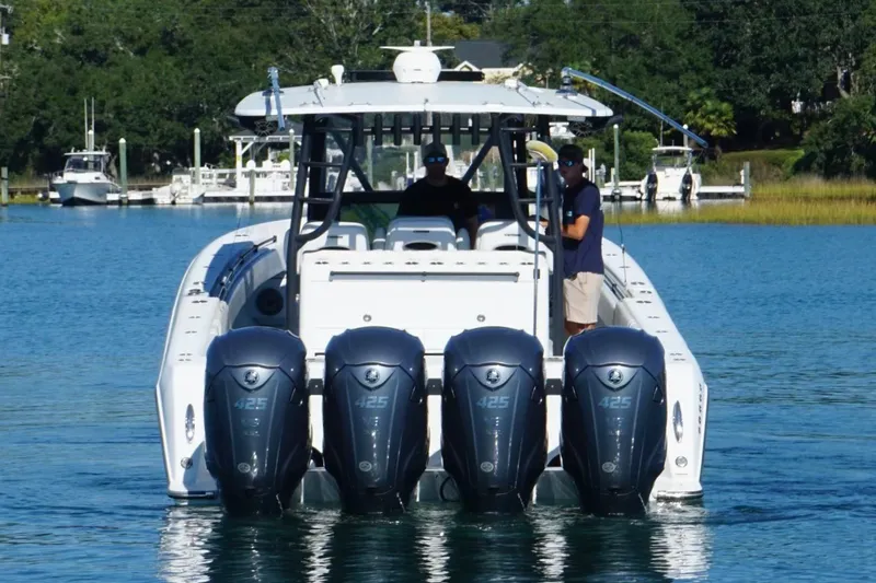 Slide: The Image of 2023 Contender 44 ST boat with four powerful outboard engines on a calm waterway. - 8