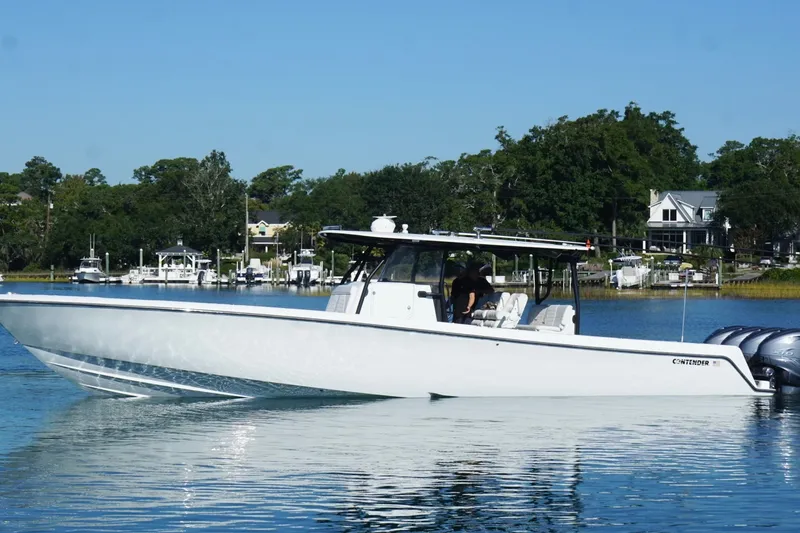 Slide: The Image of 2023 Contender 44 ST boat on calm water, surrounded by lush greenery and waterfront homes. - 16