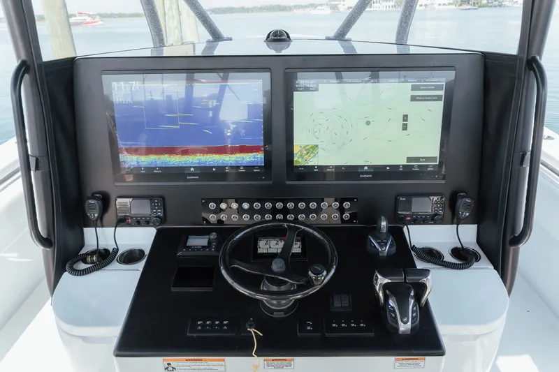 Slide: The Image of 2023 Contender 44 ST boat dashboard with dual Garmin displays and navigation controls. - 20