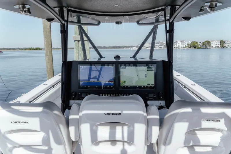 Slide: The Image of 2023 Contender 44 ST boat cockpit with dual navigation screens, overlooking calm waters. - 30