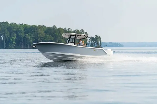 Slide: The Image of A 2027 Sea Hunt Gamefish 25 speeds across calm water, surrounded by trees. - 2