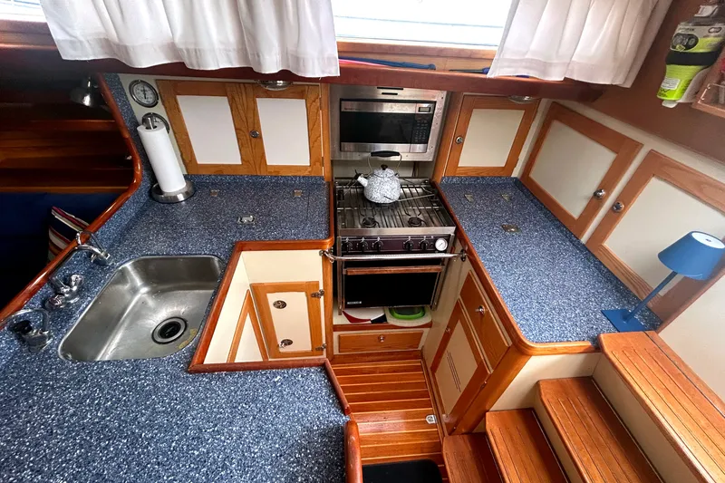 Slide: The Image of Cozy 1993 Alden 43 yacht kitchen with blue countertops, stove, and wooden cabinetry. - 13