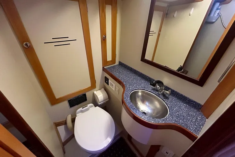 Slide: The Image of Compact bathroom in a 1993 Alden 43 yacht, featuring a sink, toilet, and mirror. - 24