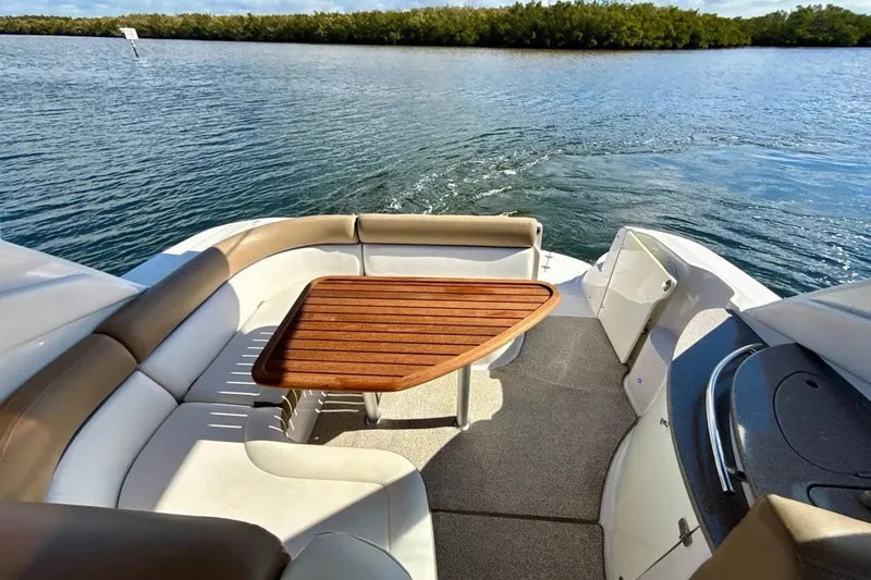 Slide: The Image of 2016 Four Winns V335 boat interior with seating and wooden table, overlooking serene water. - 3
