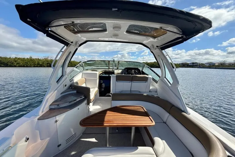 Slide: The Image of 2016 Four Winns V335 boat interior with seating and table on a sunny day. - 2