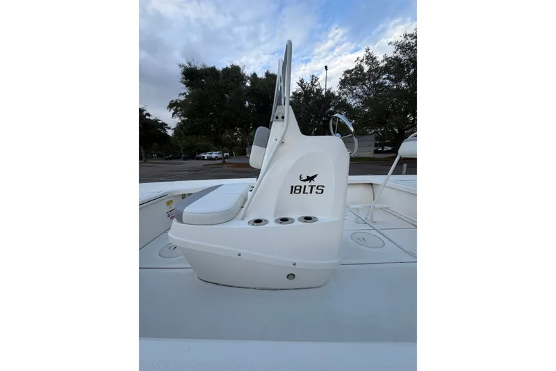 Slide: The Image of 2025 Mako 18 LTS boat interior with seating and console, under a cloudy sky. - 2