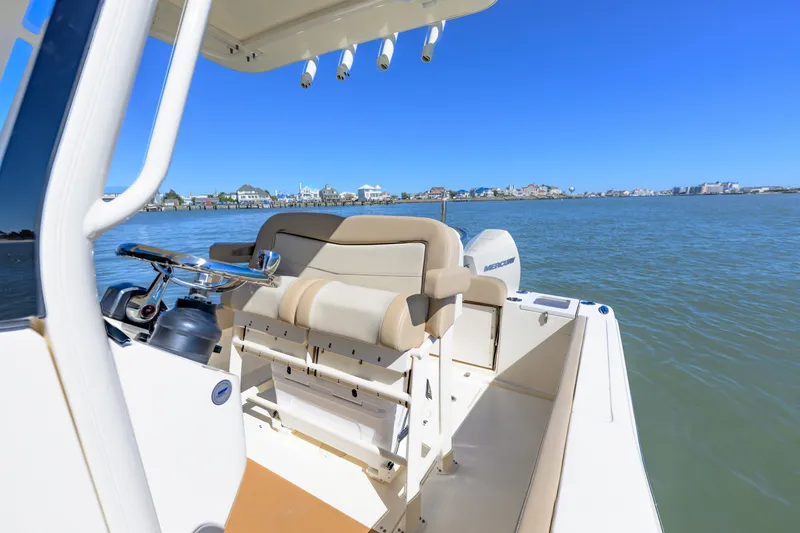 Slide: The Image of 2024 Scout 240 XSF boat interior with helm, on calm water, clear blue sky. - 8