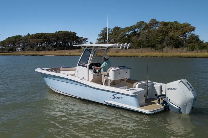 Slide: The Image of 2024 Scout 240 XSF boat cruising on a calm lake with scenic forest backdrop. - 1
