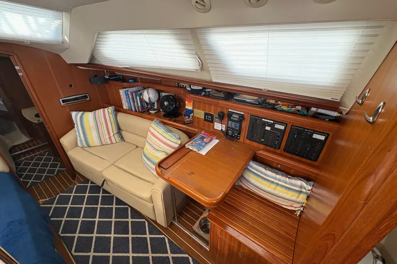 Slide: The Image of 2007 Hunter 41 Deck Salon interior with cozy seating, striped pillows, and navigation equipment. - 18
