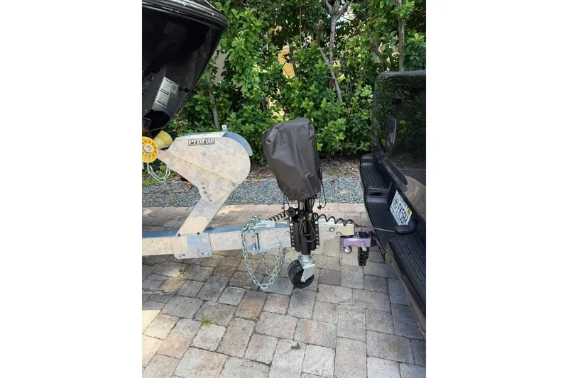 Slide: The Image of Trailer hitch setup with covered jack, connected to a vehicle, on a paved driveway. - 12