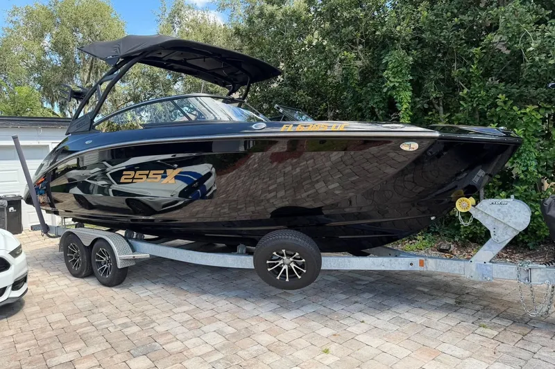 The Image of 2026 Ymaha 255X boat on trailer, sleek black design, parked on brick driveway. - 0
