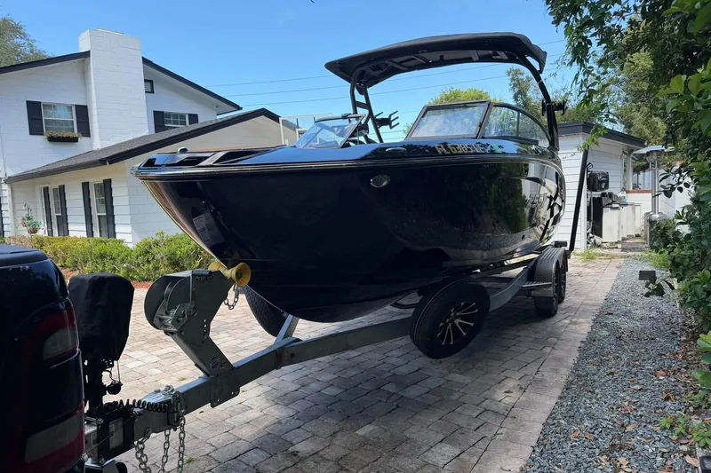 Slide: The Image of 2026 Ymaha 255 boat on trailer in residential driveway, surrounded by greenery. - 2