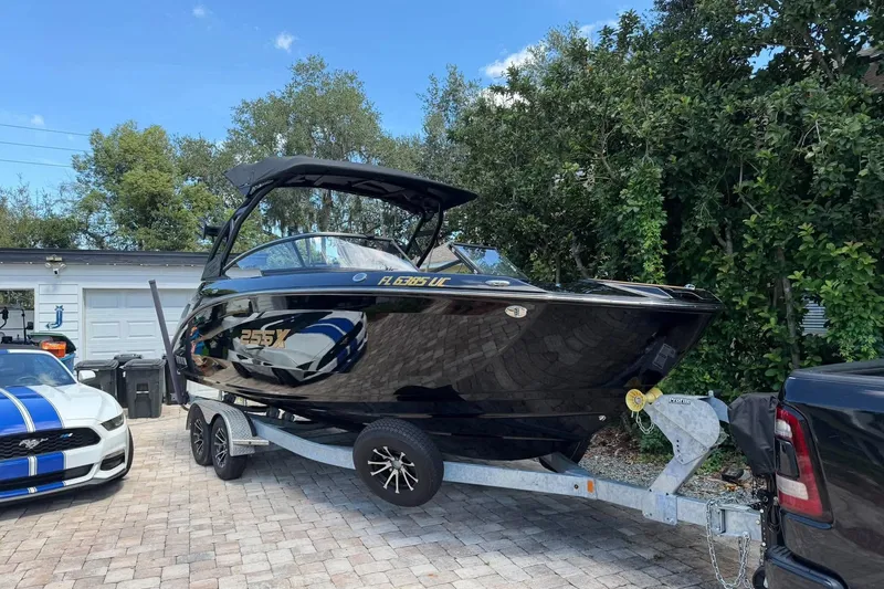 Slide: The Image of 2026 Ymaha 255 boat on trailer, parked beside a car, in a driveway. - 1