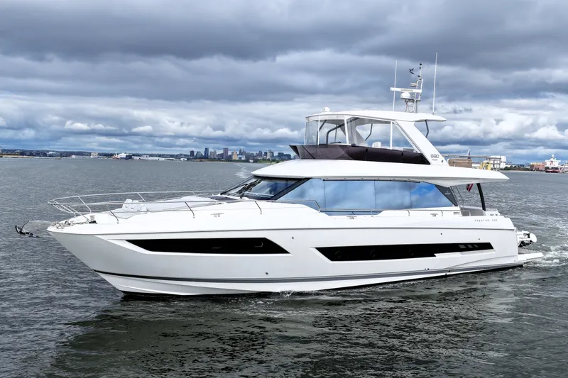 Slide: The Image of 2023 Prestige 690 yacht cruising on a cloudy day near city skyline. - 7