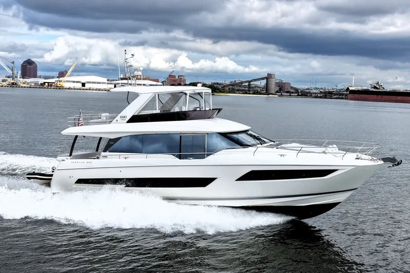Slide: The Image of 2023 Prestige 690 yacht cruising on a cloudy day near an industrial port. - 11