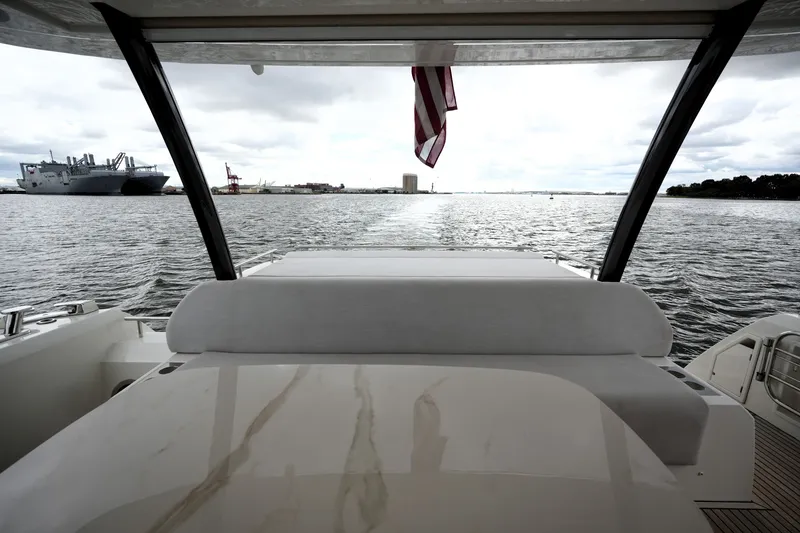 Slide: The Image of Prestige 690 yacht interior view, overlooking a harbor with ships and cranes, 2023 model. - 20