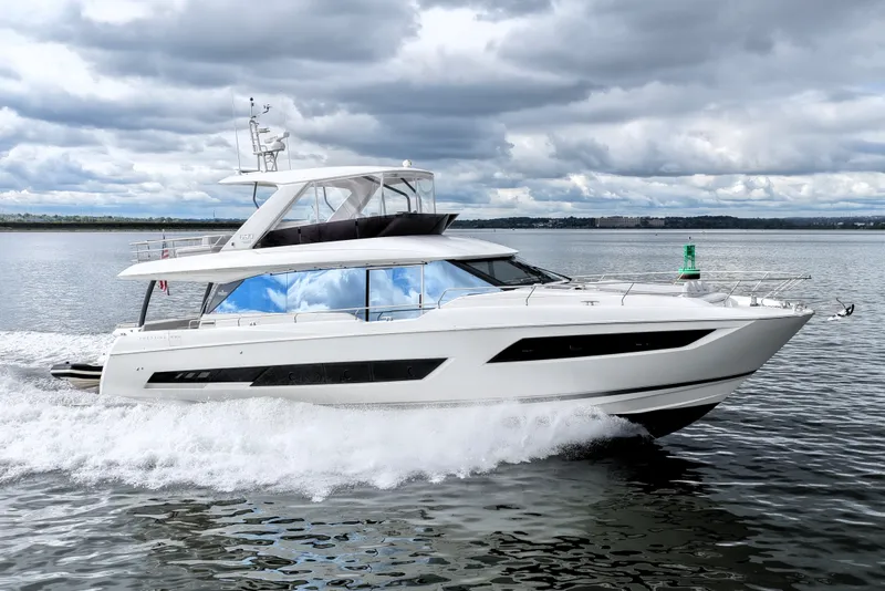 Slide: The Image of 2023 Prestige 690 yacht cruising on open water under cloudy skies. - 15