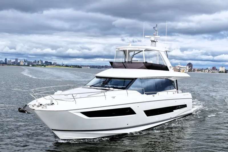 Slide: The Image of Luxury 2023 Prestige 690 yacht cruising near city skyline under cloudy skies. - 6