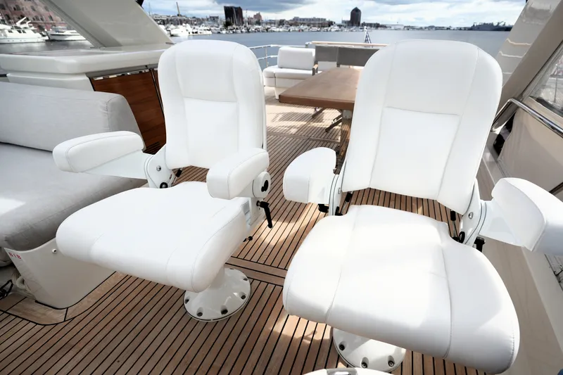 Slide: The Image of Luxury seating on 2023 Prestige 690 yacht deck, featuring white cushioned chairs and wooden flooring. - 43