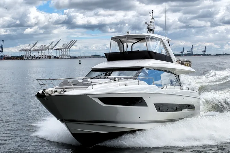 Slide: The Image of 2023 Prestige 690 yacht cruising in a harbor with cranes in the background. - 8