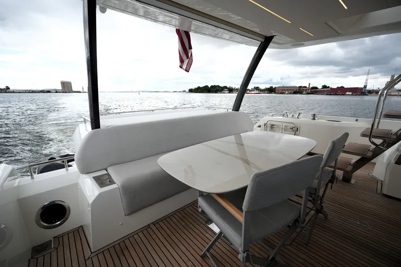 Slide: The Image of Prestige 690 yacht deck with seating and table, overlooking a scenic waterfront view. - 19