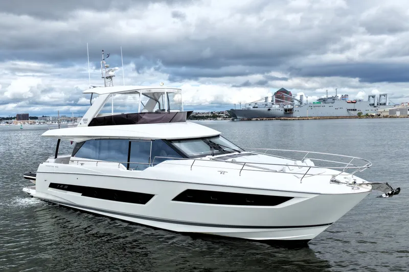 Slide: The Image of 2023 Prestige 690 yacht cruising on a cloudy day near a harbor. - 5