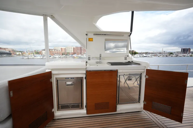 Slide: The Image of Outdoor kitchen on 2023 Prestige 690 yacht with open cabinets, overlooking marina. - 39