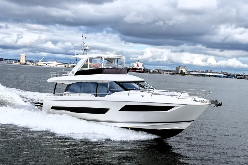 Slide: The Image of Luxury 2023 Prestige 690 yacht cruising in a scenic harbor under cloudy skies. - 13