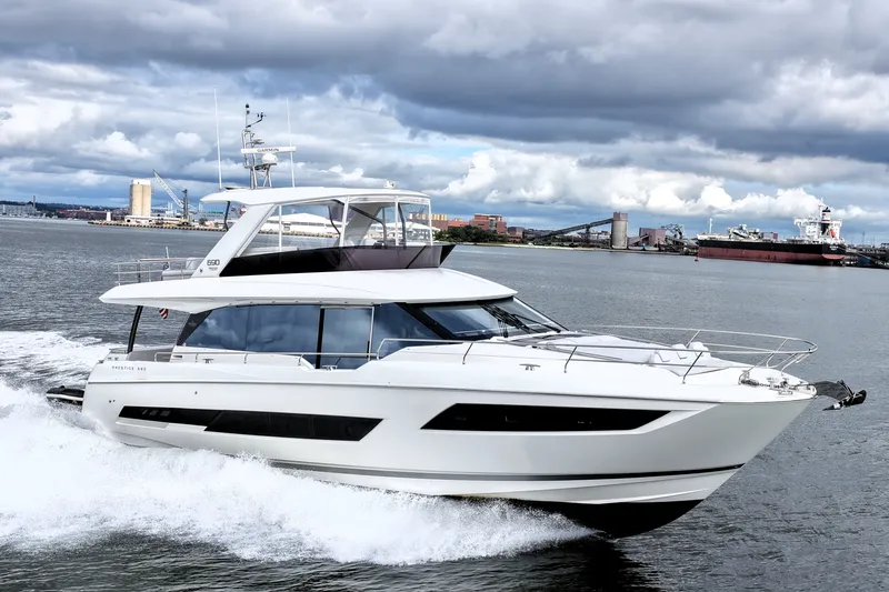 The Image of 2023 Prestige 690 yacht cruising on a scenic waterway under cloudy skies. - 0