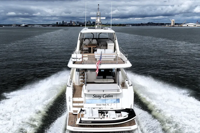 Slide: The Image of Luxury 2023 Prestige 690 yacht cruising with city skyline in the background. - 12