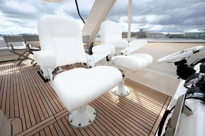 Slide: The Image of Luxurious 2023 Prestige 690 yacht helm with white captain chairs and wooden deck. - 42