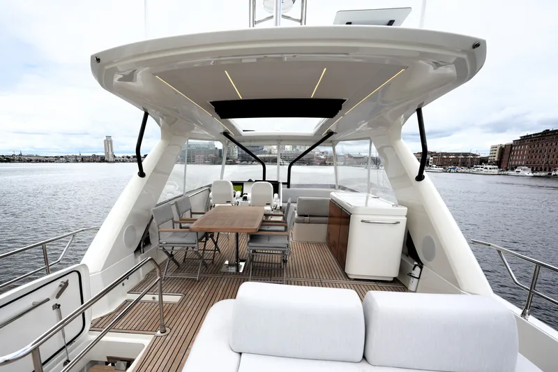 Slide: The Image of Luxurious 2023 Prestige 690 yacht deck with elegant seating and dining area, overlooking a serene waterfront. - 4