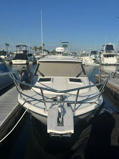 Slide: The Image of A 2026 Cutwater C-248 Coupe docked in a marina, surrounded by other boats. - 2
